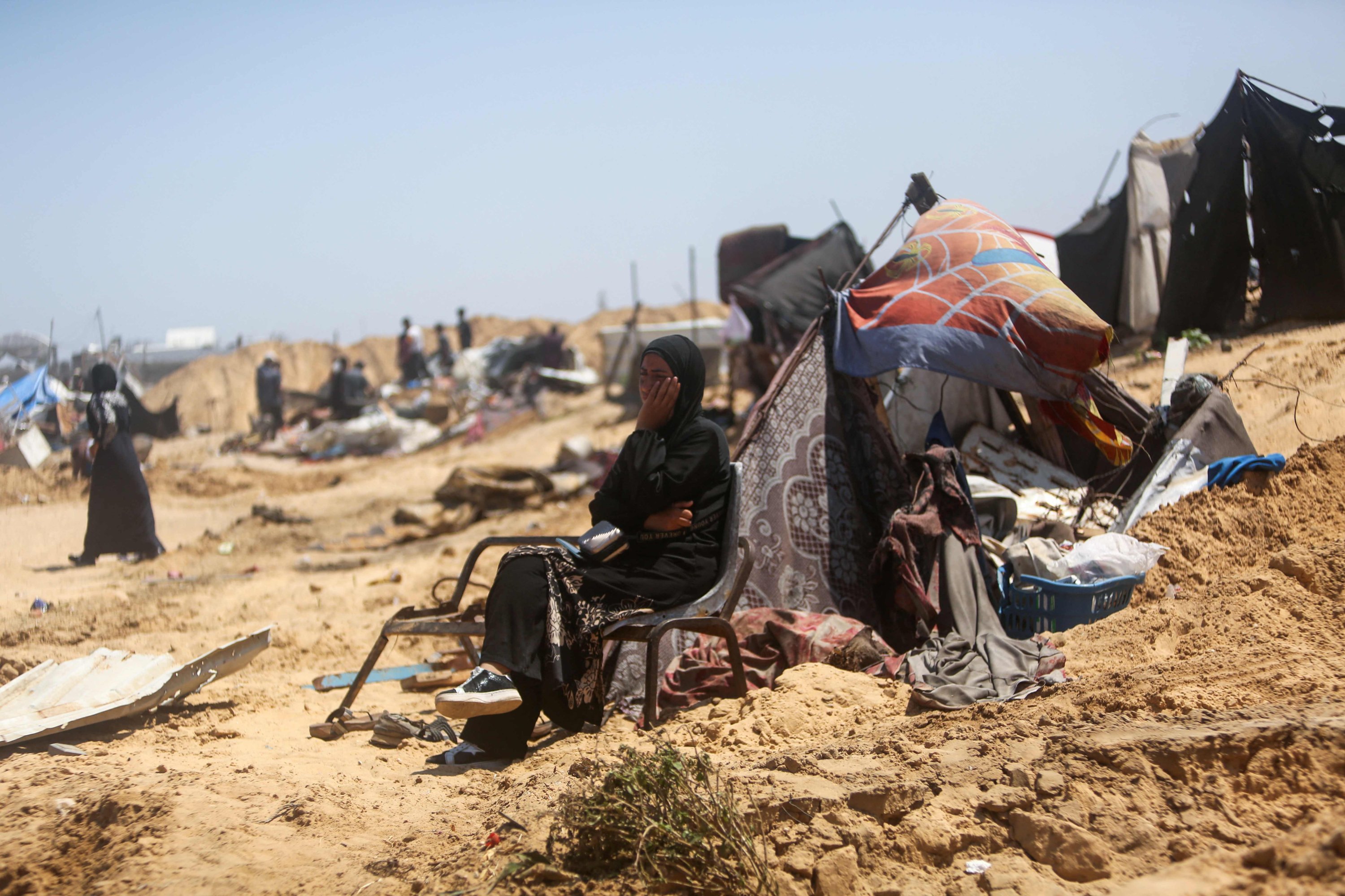A woman sitting by salvaged belongings looks on as Palestinians inspect the destruction at a makeshift displacement camp following a Israeli incursion, in Khan Yunis, southern Gaza Strip, Palestine, July 11, 2025. (AFP Photo)