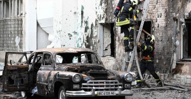 Firefighters are seen next to a burnt-out car following mass Russian drone and missile strikes, in Lviv, western Ukraine, July 12, 2025. (AFP Photo)