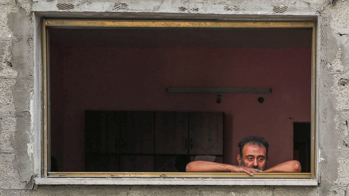 A man looks out of a window as Palestinians inspect the site and search for casualties of an overnight Israeli airstrike on a house at al-Shati refugee camp, Gaza City, central Gaza, Palestine, July 15, 2025. (Reuters Photo)