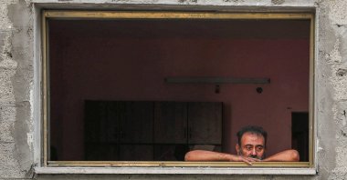 A man looks out of a window as Palestinians inspect the site and search for casualties of an overnight Israeli airstrike on a house at al-Shati refugee camp, Gaza City, central Gaza, Palestine, July 15, 2025. (Reuters Photo)