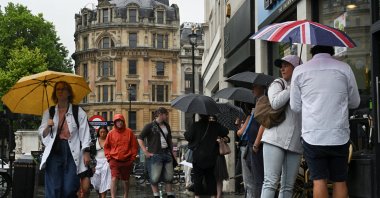 People walk at Trafalgar Square while carrying umbrellas during rainy weather after a heat wave in previous days, London, U.K., July 2, 2025. (Reuters Photo)