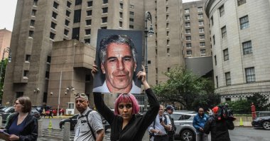A member of a protest group called &quot;Hot Mess&quot; holds up a sign of Jeffrey Epstein in front of the Metropolitan Correction Center, New York City, U.S., July 8, 2019. (AFP Photo)