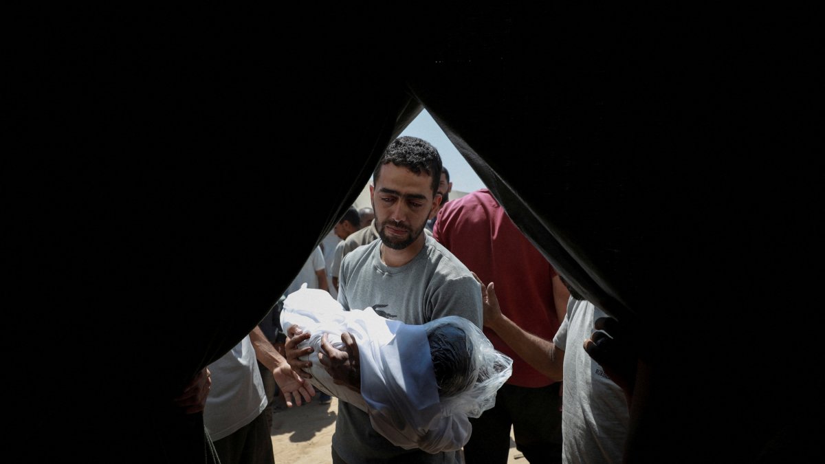A mourner carries the body of a child during the funeral of Palestinians from the Azzam family, killed in an overnight Israeli strike on their house, according to medics, before burying them in a plot of land due to the lack of space in Gaza's overcrowded cemeteries, in Gaza City July 15, 2025. (Reuters Photo)