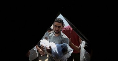 A mourner carries the body of a child during the funeral of Palestinians from the Azzam family, killed in an overnight Israeli strike on their house, according to medics, before burying them in a plot of land due to the lack of space in Gaza's overcrowded cemeteries, in Gaza City July 15, 2025. (Reuters Photo)