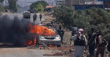 Bedouin and tribal fighters deploy as a car burns at the western entrance of Syria&#039;s Druze heartland of Sweida, July 18, 2025. (AFP Photo)