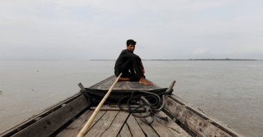 A man sits in a boat on the waters of the Brahmaputra river near the international border between India and Bangladesh in the Dhubri district, in the northeastern state of Assam, India, Aug. 4, 2018. (Reuters Photo)