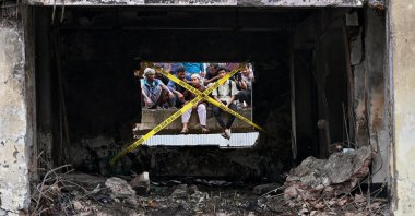 Onlookers gathered behind crime scene barrier tape, cordoning off the crash site in Dhaka, Bangladesh, July 22, 2025. (AFP Photo)