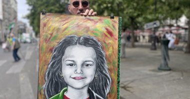 Algerian artist Aboulhak Abina holds his painting of Palestinian child Hind Rajab, who was killed by the Israeli army, Paris, France, July 5, 2025. (AA Photo)