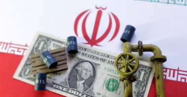 An Iranian flag, a U.S dollar banknote and minatures of oil pipes and barrels are seen in this illustration taken June 23, 2025. (Reuters Photo)