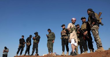 A Beduin member stands with Syrian government forces atop an earth barrier that they created as a buffer during their deployment, Busra al-Harir, Syria, July 21, 2025. (AFP Photo)