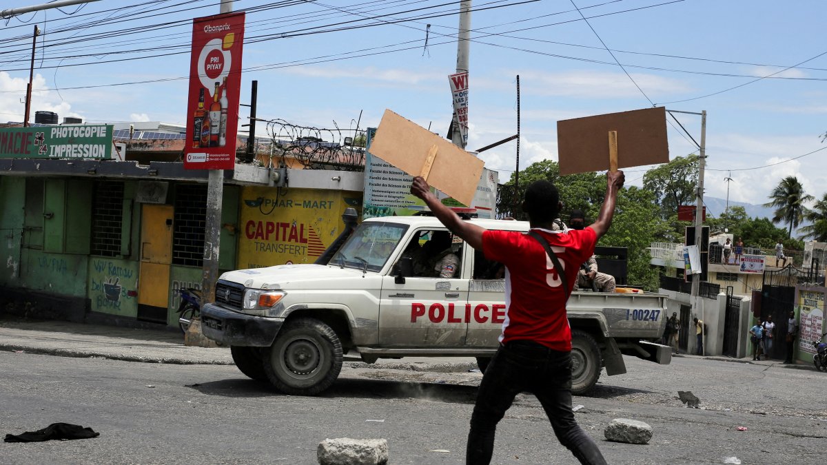 A man holds up placards as he yells toward a patrol car during a protest against gang-related violence and to demand the resignation of Haiti&#039;s transitional presidential council, Port-au-Prince, Haiti, May 15, 2025. (Reuters Photo)
