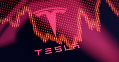 Tesla logo and a decreasing stock graph are seen in this illustration taken on July 23, 2025. (Reuters Photo)