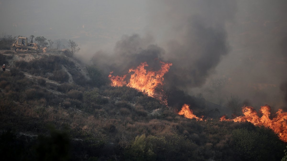 A bulldozer is seen near flames during a wildfire in Omodos village, the island of Cyprus, July  24, 2025. (Reuters Photo)