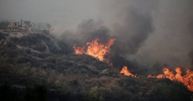 A bulldozer is seen near flames during a wildfire in Omodos village, the island of Cyprus, July  24, 2025. (Reuters Photo)