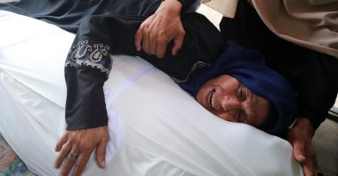 A lady reacts as she holds a body at a funeral of Palestinians killed by Israeli fire while trying to receive aid and others who were killed in an overnight Israeli strike, according to medics, at Al-Shifa Hospital in Gaza City, July 26, 2025. (Reuters Photo)