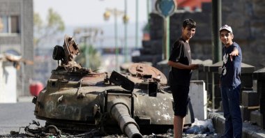 People stand next to a destroyed tank turret, following deadly clashes between Druze fighters, Sunni Bedouin tribes and government forces, in Syria&#039;s predominantly Druze city of Sweida, Syria July 25, 2025. (Reuters Photo)