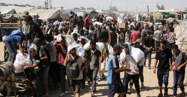 People carry food parcels and bags in the al-Mawasi camp in Rafah in the southern Gaza Strip, Palestine, July 27, 2025. (AFP Photo)