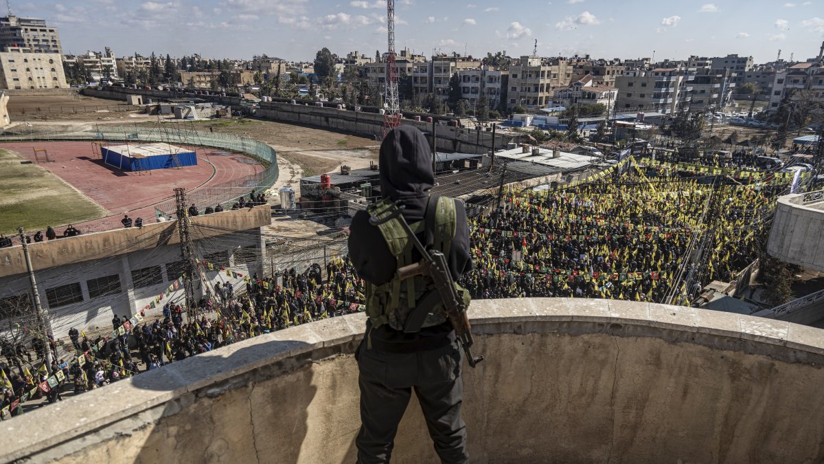 A YPG terrorist watches demonstrators in Qamishli, Syria, Feb. 15, 2025. (AP Photo)
