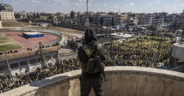 A YPG terrorist watches demonstrators in Qamishli, Syria, Feb. 15, 2025. (AP Photo)
