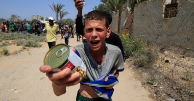 A Palestinian youth holds a can of chickpeas from an aid package dropped from an airplane, amid a hunger crisis, in Zawayda, central Gaza Strip, Palestine, July 28, 2025. (Reuters Photo)
