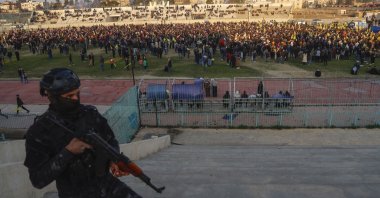 A YPG terrorist watches as hundreds attend a gathering to listen to a statement from the jailed leader of the PKK terrorist group, Qamishli, Syria, Feb. 27, 2025. (AP Photo)