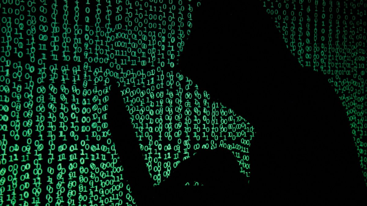 A hooded man holds a laptop computer as cyber code is projected on him in this illustration picture, May 13, 2017. (Reuters Photo)