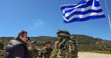 Defense Minister Panos Kammenos (L) speaks with Greek soldiers in front of a Greek flag as he attends a reservist exercise on the eastern island of Ikaria, Greece, April 4, 2018. (AP Photo)