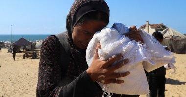 Displaced Palestinian mother Zainab Dakka reacts as she holds a bag of flour outside her tent, after returning from an aid delivery that entered Gaza through Israel, in Gaza City, central Gaza, Aug. 1, 2025. (Reuters Photo)