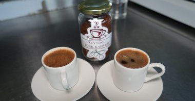 Two cups of freshly brewed Turkish coffee sit beside a box of olive-infused Turkish coffee, Ayvalık, Türkiye, Aug. 3, 2025. (IHA Photo)