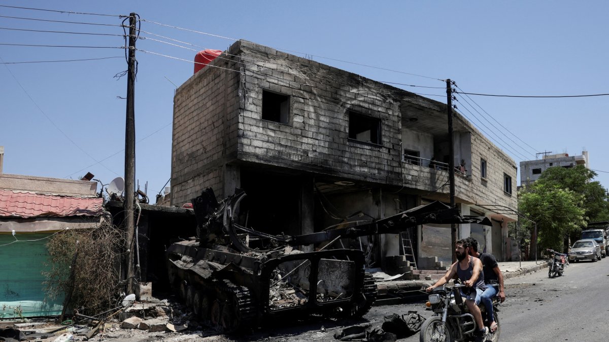 People ride a motorcycle past a burned-out military vehicle, following deadly clashes between armed forces in Syria&#039;s predominantly Druze city, Suwayda, Syria, July 25, 2025. (Reuters Photo)