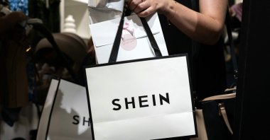 A customer holds her bags as she exits a pop-up store of the Chinese-founded fast fashion brand Shein, Dijon, France, June 26, 2025. (AFP Photo)