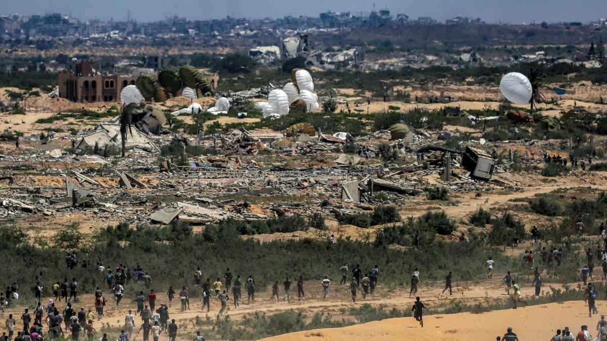 Palestinians rush to the scene as air pallets, carrying humanitarian aid, parachute down after being dropped from a military plane over Nuseirat in the central Gaza Strip during an airdrop mission above the Israel-besieged Palestinian territory, Aug. 5, 2025. (AFP Photo)