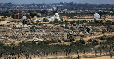 Palestinians rush to the scene as air pallets, carrying humanitarian aid, parachute down after being dropped from a military plane over Nuseirat in the central Gaza Strip during an airdrop mission above the Israel-besieged Palestinian territory, Aug. 5, 2025. (AFP Photo)