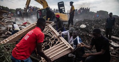 Men fight for a metallic door from the debris of a house hit by a landfill collapse, Kampala, Uganda, Aug. 10, 2024. (AFP Photo)