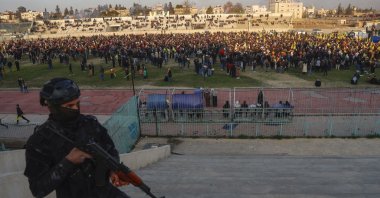 A YPG terrorist watches as hundreds attend a gathering to listen to a statement from the jailed leader of the PKK terrorist group, Qamishli, Syria, Feb. 27, 2025. (AP Photo)