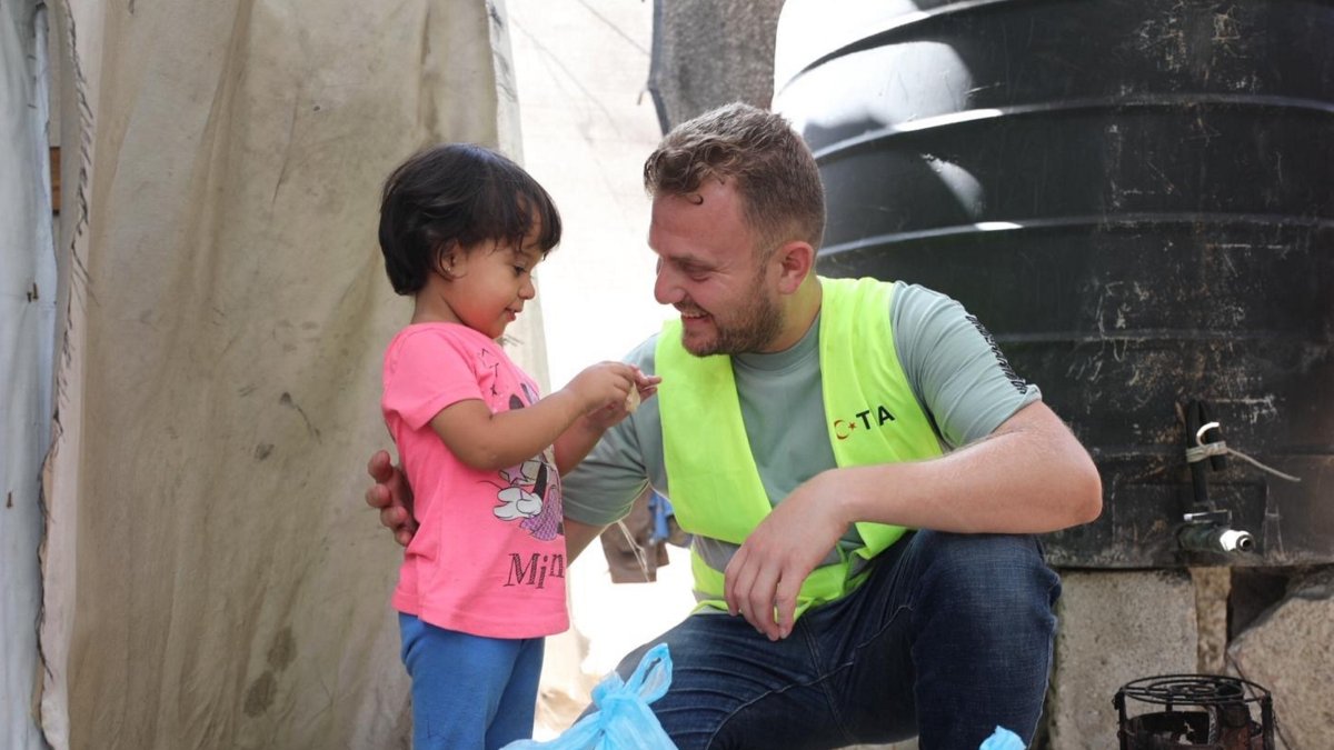 A TIKA volunteer hands a food package to a young girl in Gaza amid ongoing humanitarian challenges, Gaza, Palestine, Aug. 9, 2025. (AA Photo)
