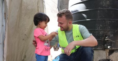 A TIKA volunteer hands a food package to a young girl in Gaza amid ongoing humanitarian challenges, Gaza, Palestine, Aug. 9, 2025. (AA Photo)