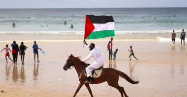 Senegalese artist Thierno Gueye carries the Palestinian flag on horseback to show solidarity with Gaza at Yoff Beach, Dakar, Senegal, Aug. 10, 2025. (AA Photo)