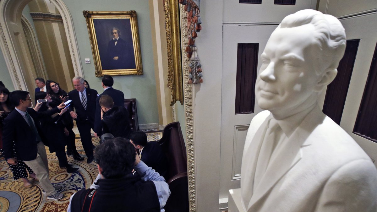 A bust of former President Richard Nixon looks is on display in the hallway outside the Senate chamber as Senator Ron Johnson (center back) talks to reporters, prior to the start of the impeachment trial of President Donald Trump at the U.S. Capitol, Washington, U.S., Jan 31, 2020. (AP Photo)