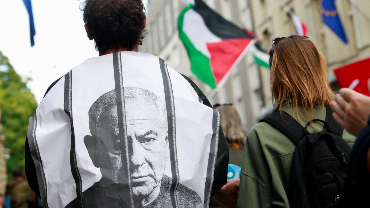 A pro-Palestinian activist is wrapped in an image depicting Israeli Prime Minister Benjamin Netanyahu behind bars as demonstrators march, Ljubljana, Slovenia, Aug. 6, 2025. (Reuters Photo)