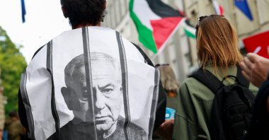 A pro-Palestinian activist is wrapped in an image depicting Israeli Prime Minister Benjamin Netanyahu behind bars as demonstrators march, Ljubljana, Slovenia, Aug. 6, 2025. (Reuters Photo)