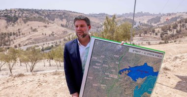 Israeli far-right Finance Minister Bezalel Smotrich holds a map of an area near the settlement of Maale Adumim, a land corridor known as E1, outside Jerusalem in the occupied West Bank, Aug. 14, 2025. (AFP Photo)