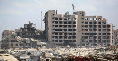 Palestinians walk on a dirt road in a makeshift displacement camp on the Gaza City beachfront, across from the Ayan Hotel, formerly Al-Mashtal, that was destroyed in Israeli strikes, Aug. 8, 2025. (AFP Photo)