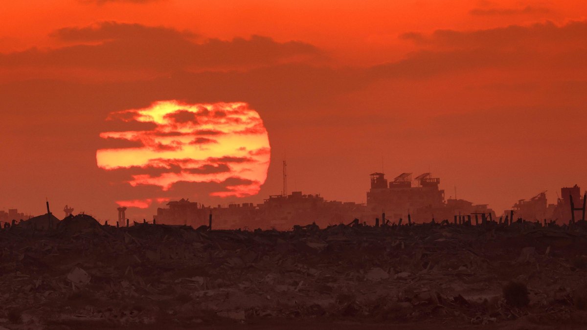 In this picture taken from a position on the Israeli border with the Gaza Strip, the sun sets behind destroyed buildings in the Palestinian territory, Aug. 7, 2025. (AFP Photo)