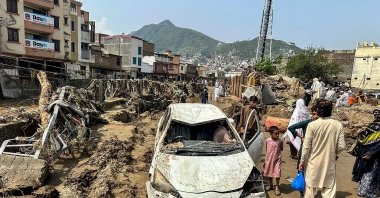 People gather near a damaged vehicle and scattered debris after the road washed out following a flash flood in Mingora, the main city of Swat Valley, in monsoon-hit northern mountainous Khyber Pakhtunkhwa province, Pakistan, Aug. 16, 2025. (AFP Photo)