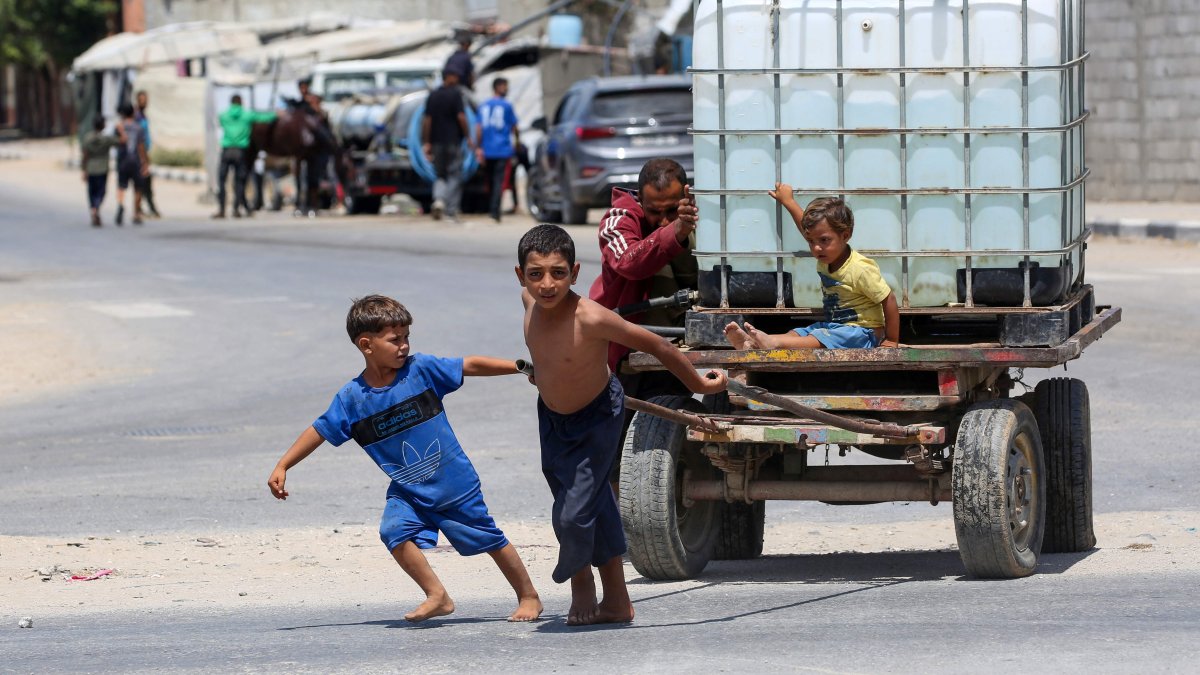 A man and young children push on a cart carrying a water tank at the Bureij camp for displaced Palestinians in the central Gaza Strip, Aug. 17, 2025. (AFP Photo)