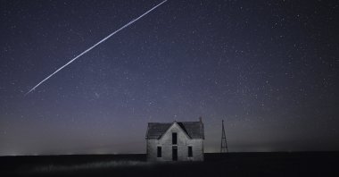 In this long exposure photo, a string of SpaceX StarLink satellites passes over an old stone house near Florence, Kansas, U.S., May 6, 2021. (AP Photo)