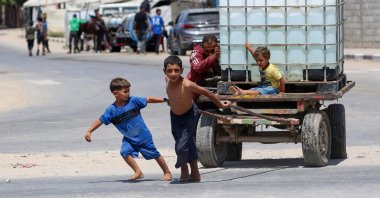 A man and young children push on a cart carrying a water tank at the Bureij camp for displaced Palestinians in the central Gaza Strip, Aug. 17, 2025. (AFP Photo)