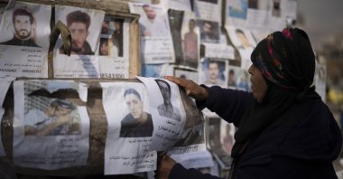 A woman places a photo, among others, of a person reported to be missing by members of Bashar Assad's army, or a pro-government militia, in the Marjeh square in Damascus, Syria, Sunday, Dec. 22, 2024. (AP File Photo)