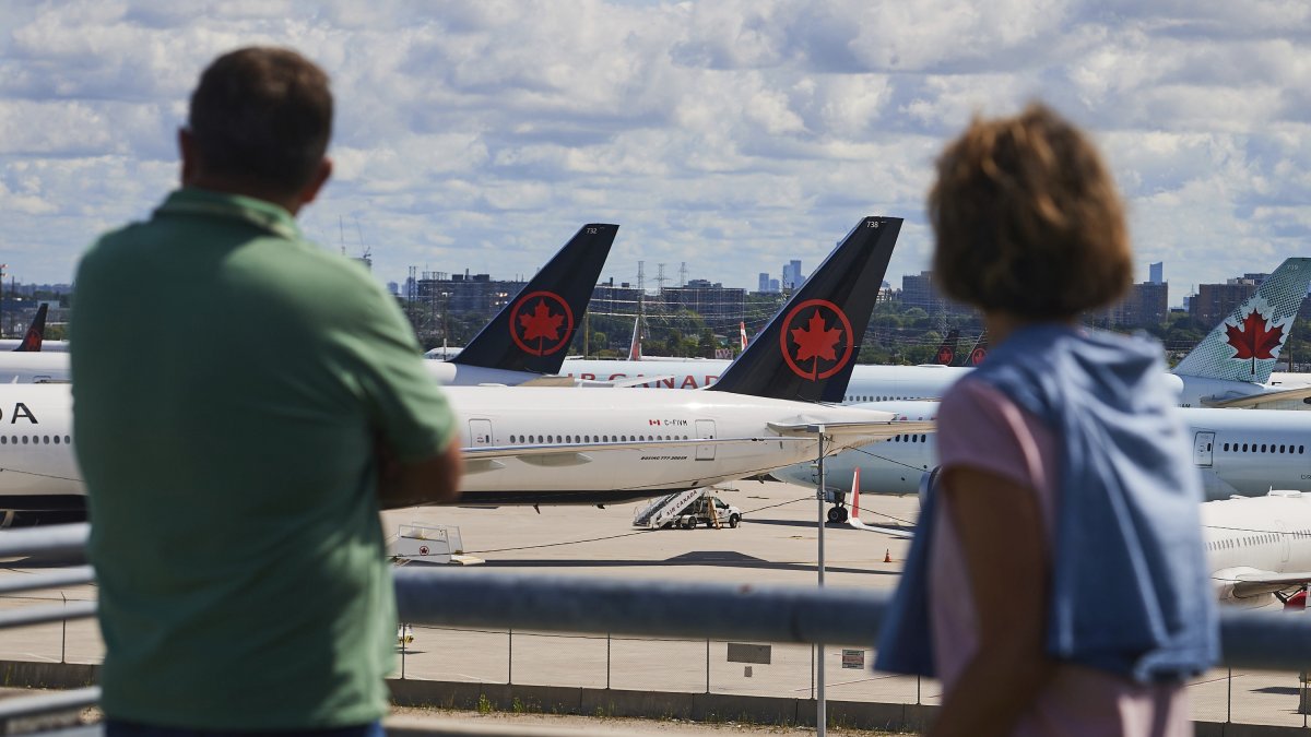 Travelers look out over grounded Air Canada planes as flight attendants picket at Pearson International Airport, Toronto, Canada, Aug. 18, 2025. (AP Photo)